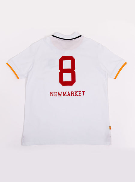 Flat lay of men's white polo shirt in 100% cotton with Newmarket 875 crest embroidered on the front and giant red 8 on the back with navy sleeve trimming and gold collar trimming.